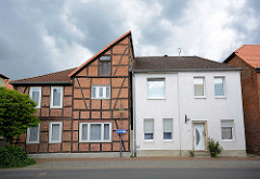 Historische und neue Architektur nebeneinander - Wohnhäuser in Lüchow; Fachwerkhaus mit halben Spitzdach / Giebel, kubisches Gebäude mit weisser Fassade.