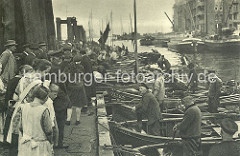 Fischerboote haben am Ponton des Altonaer Fischmarktes angelegt. Die Fischer an Bord preisen Ihre Ware an - die Besucher und Besucherinnen des Fischmarktes gehen an den Booten entlang und begutachten die Fische.  (ca. 1928)