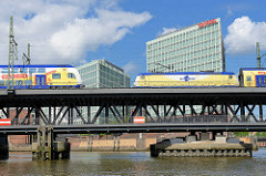 Oberhafenbrücke über den Oberhafenkanal; zwei Metronomzüge überqueren die Strassenbrücke / Eisenbahnbrücke; Stahlkonstrukiton auf zwei Etagen; im Hintergrund das Verwaltungsgebäude vom Spiegelverlag an der Ericusspitze im Hamburger Stadtteil Hafencit
