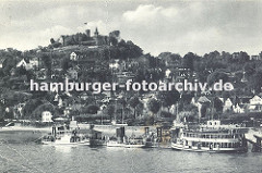 Ansicht vom alten Hamburg Blankenese - drei Ausflugsschiffe haben am Anleger festgemacht. Eine Wassertreppe führt vom Ponton zum Ufer. Auf der Spitze des Süllbergs die Türme des Restaurants.