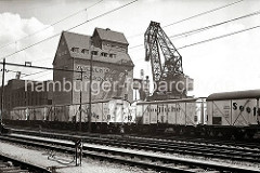 Auf den Gleisanlagen der Hafenbahn stehen Güterwaggons für den Fischtransport; dahinter am Hafenkai des Altonaer Hafen ein 40 Tonnen Doppellenker-Wippkran und der Getreidespeicher.  (ca. 1938)