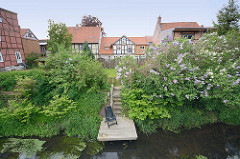 Blick über die Drawehner Jeetzel in Lüchow - Garten mit blühendem Flieder am Wasser; Fachwerkhäuser.