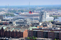 Blick über die Gebäude und Dächer der Hamburger Hafencity - hinter dem Marco Polo Tower liegt das Kreuzfahrtschiff QUEEN MARY am Terminal an der Norderelbe.