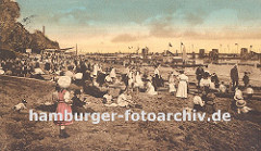 historisches Foto einer Strandszene an der Elbe bei Altona, Oevelgoenne / Neumühlen. Die Kinder sitzen in ihren Kleidern im Sand, ein Hund sieht dem Treiben zu. Frauen / Mütter mit Sonnenhüten und Kleidern und Männer mit Strohhüten oder Mützen si