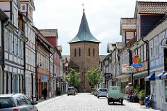 Blick durch die Kirchstrasse in Lüchow zum Kirchturm der St. Johanneskirche. Fachwerkhäuser mit Wohnungen und Geschäften.