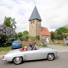 Kirche, Kapelle in Luckau / Wendland; gotischer Felssteinbau, rechteckiger Glockenturm - Mercedes Cabrio in Fahrt.