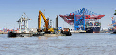 Im Parkhafen vor dem Waltershofer Hafen wird die Elbe ausgebaggert - ein Bagger auf einem Schwimmponton füllt das Baggergut in eine Schute - im Hintergrund Containerbrücken vom Terminal Burchardkai.