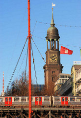 Hochbahnviadukt mit Hochbahn am Baumwall in Hamburg - Kirchturm der St. Michaeliskiche - eine Hamburg Flagge weht im Wind.