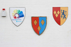 Wappen im Landkreis Lüchow-Dannenberg an der Fassade vom Rathaus in Lüchow; lks. der Samtgemeinde Lüchow, in der Mitte der Stadt Lüchow - lks. das moderne Wappen Wendland mit angedeutetem Runddorf.
