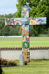 Geschnitzes farbiges Holzkreuz bei der Kirche von Luckau - angefertigt als Ferienaktion von Kindern und Jugendlichen unter der Anleitung des Künstlers Johann-Reimer Schulz.