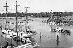 Blick von Finkenwerder Richtung Elbe ca. 1939; ein Segelschiff liegt am Steg - es ist mit Tauen an den Duckdalben fest gemacht. Eine Hafenfähre hat von den Finkenwerder Landungsbrücken abgelegt und fährt Richtung Elbe. Dahinter ist das Hamburger L