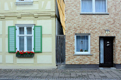 Alt + neu; Wohnhäuser in der Kyritzer Strasse von Wusterhausen, Dosse - Fachwerkhaus, restauriert mit Fensterluken und Blumenkasten - Hausfassade mit Ziegelverkleidung.