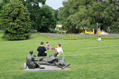 Liegewiese auf der Freundschaftsinsel in Potsdam - Menschen und Bronzeskulptur - Schönheit der Menschen in der Natur, Margret Midell, 1974; im Hintergrund fährt auf der Havel, Neue Fahrt ein Ausflugsschiff.
