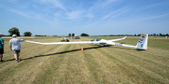 Der Doppelsitzer DG 1001 wird auf dem Kyritzer Segelflugplatz nach der Landung mit dem Flugzeuschlepper zur Startbahn gezogen.