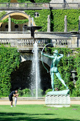 Gartenanlage mit Bronzeskulptur Bogenschütze vor dem Orangerieschloss im Potsdamer Park Sanssouci.