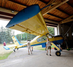 Vereinsmitglieder vom Flugsport-Club Kyritz schieben das Schleppflugzeug PZL-104 Wilga zur Halle.