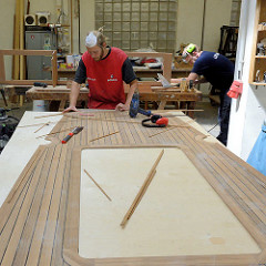 Die Kanten des Mahagonie-Decks werden in der Werkstatt mit Massivholzleisten versehen.