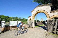 Eingang mit Holztoren, Holzgitter zum Park Sanssouci, Potsdam - Schilder mit Parkordnung und Kasten für freiwillige Spenden - Fahrradfahrer Richtung Linnéstrasse.
