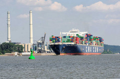 Der Containerfrachter CMA CGM Amerigo Vespucci auf der Elbe vor Wedel - am Ufer die Schornsteine und das Heizkraftwerk Wedel. Die Amerigo Vespucci hat eine Länge von 365 m und kann 13830 TEU Container transportieren.