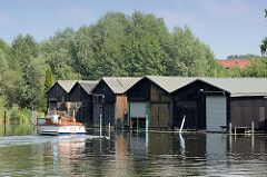 Bootshäuser an der Havel bei Zehdenick - ein Sportboot fährt in den Hafen ein.