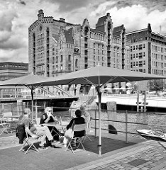 Cafe am Ufer des Magdeburger Hafens in der Hamburger Hafencity - im Hintergrund der ehem. Kaispeicher B, das jetzige Hamburger Maritime Museum.