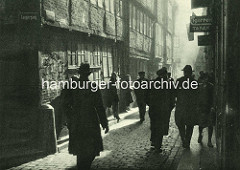 Alte Fotos aus dem Gängeviertel Hamburgs -  Männer mit Hut Ecke Langer Gang / Kornträgergang - Frauen haben sich wartend an die Hauswand gelehnt.