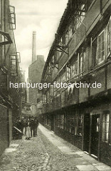 Historische Bilder aus dem Hamburger Gängeviertel - Wohnhäuser im Brauerknechtsgraben - Gruppenfoto, Frauen sehen aus dem geöffneten Fenster - Fabrikschornstein.