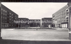 Historische Ansicht vom Semperplatz in der Hamburger Jarrestadt; frisch gepflanzte Bäume. im Hintergrund das Wohngebäude entworfen von den Architekten Grell &  Pruter; das rechte Gebäude wurde vom Architekten Robert Friedmann entworfen, den Entw