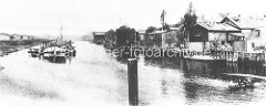 Historisches Foto vom Hafenbecken in  Hamburg Rothenburgsort - Lastkähne liegen an Dalben im Wasser; Gewerbegebäude sind direkt an die Wasserseite gebaut / Schiffe werden an der Kainalage entladen.