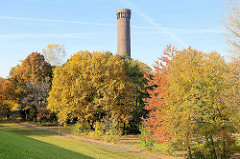 Herbst im Traunspark von Hamburg Rothenburgsort - hinter den Bäumen mit Herbstlaub der historische Wasserturm der Wasserwerke.