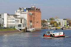 Ein Schubschiff fährt in die Billwerder Bucht in Hamburg Rothenburgsort ein  - am Ufer ein historisches Speichergebäude / Industriearchitektur.