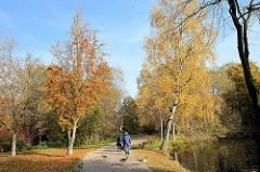 Herbstspaziergang zwischen herbstlichen Bäumen an der Wandse im Eichtalpark von Hamburg Wandsbek.