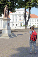 Blick auf das Schloss Oranienburg - eine Touristin fotografiert das Louise-Henriette-Denkmal von Wilhelm Wolff (1858).