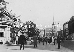 Altes Bild vom Fussweg vor dem Alsterpavillon am Jungfernstieg, Palmen stehen vor dem Restaurant - im HIntergrund das Gebäude vom Haus Vaterland und der Kirchturm der Hamburger St. Petri-Kirche.