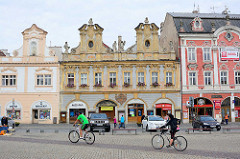 Karlsplatz / Karlovo náměstí in Kolin - städtische Architektur des späten Barock, Renaissance und klassizistischer Historismus. Barockgebäude mit Geschäften, parkende Autos - FahrradfahrerIn.