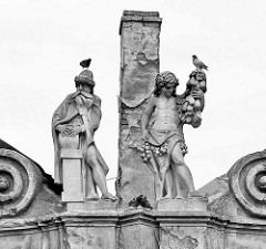 Skulpturen auf dem Dach eines historischen Hauses am Karlsplatz / Karlovo náměstí in Kolin - Tauben turteln oder sitzen auf den historischen Figuren, schiefer Schornstein.