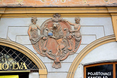 Wappenrelief, nackte Frauen - Löwe stehend auf den Hinterbeinen mit Weltkugel in den Pfoten - Hausfassade in Kolin, Tschechische Republik.