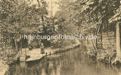 Blick in einen Fliess im Spreewald - ein Kind / Mädchen stakt eine Kahn - Wohnhäuser, Holzhütten am Ufer.