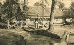 Fussgängerbrücke / Holzbrücke über einen schmalen Fliess im Spreewald - Wohnhaus mit Reet gedeckt.