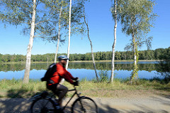 Radfahrer auf der Spreewald-Radroute bei Schlepzig - blauer Himmel, Birken am Wasser.