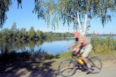 Radfahrer auf der Spreewald-Radroute bei Schlepzig - blauer Himmel, Birken am Wasser.