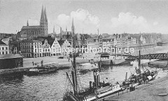 Historisches Panorama der Hansestadt Lübeck - Blick über die Trave; re. die Drehbrücke über die Trave - Lagerschuppen, Frachschiff am Kai - Rauch steigt aus dem Schornstein.