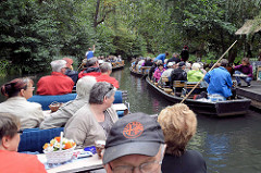 Touristentransport per Kahn in Lübbenau im Spreewald - zwei Kähne haben an einem Kiosk angelegt und lassen sich mit Gurken etc. verköstigen - zwei weitere Boote mit Passagieren fahren vorbei.