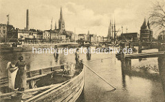 Historische Ansicht vom Lübecker Hafen - eine Frau / Schifferin hängt Wäsche auf; Masten von Segelschiffen, Motorschiff am Kai.