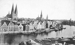 Historisches Panorama der Lübecker Altstadt - Blick über die Trave auf die Kaianlage am Ufer - Frachtsegler liegen am Kai; re. das Holstentor - Türme der Marienkirche, Petrikiche und Lübecker Dom.