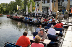 Hafen für Ausflugsboote für Touristen in Lübbenau Spreewald; die Passagiere sitzen auf Bänken an Tischen.