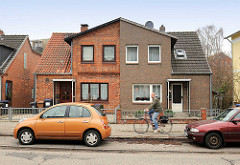 Doppelhaus mit unterschiedlich gestalteter Klinkerfassade; parkende Autos, Radfahrer - Lübeck Moisling.