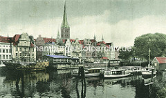 Historische Ansicht vom Altstadthafen und Gebäuden an der Trave in der Hansestadt Lübeck - Nachbau einer Kogge mit Kanonen, Barkassen; Kirchturm der Lübecker Petrikirche.