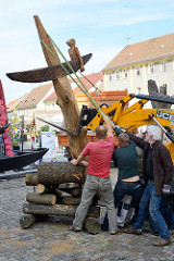 Bildhauersymposium / Spreewaldatelier in Lübbenau; eine Holzskulptur wird auf dem Kirchplatz aufgestellt.