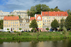 Wohnhäuser und Uferpromenade an der Neiße in Zgorzelec; polnischer Grenzpfahl am Ufer.